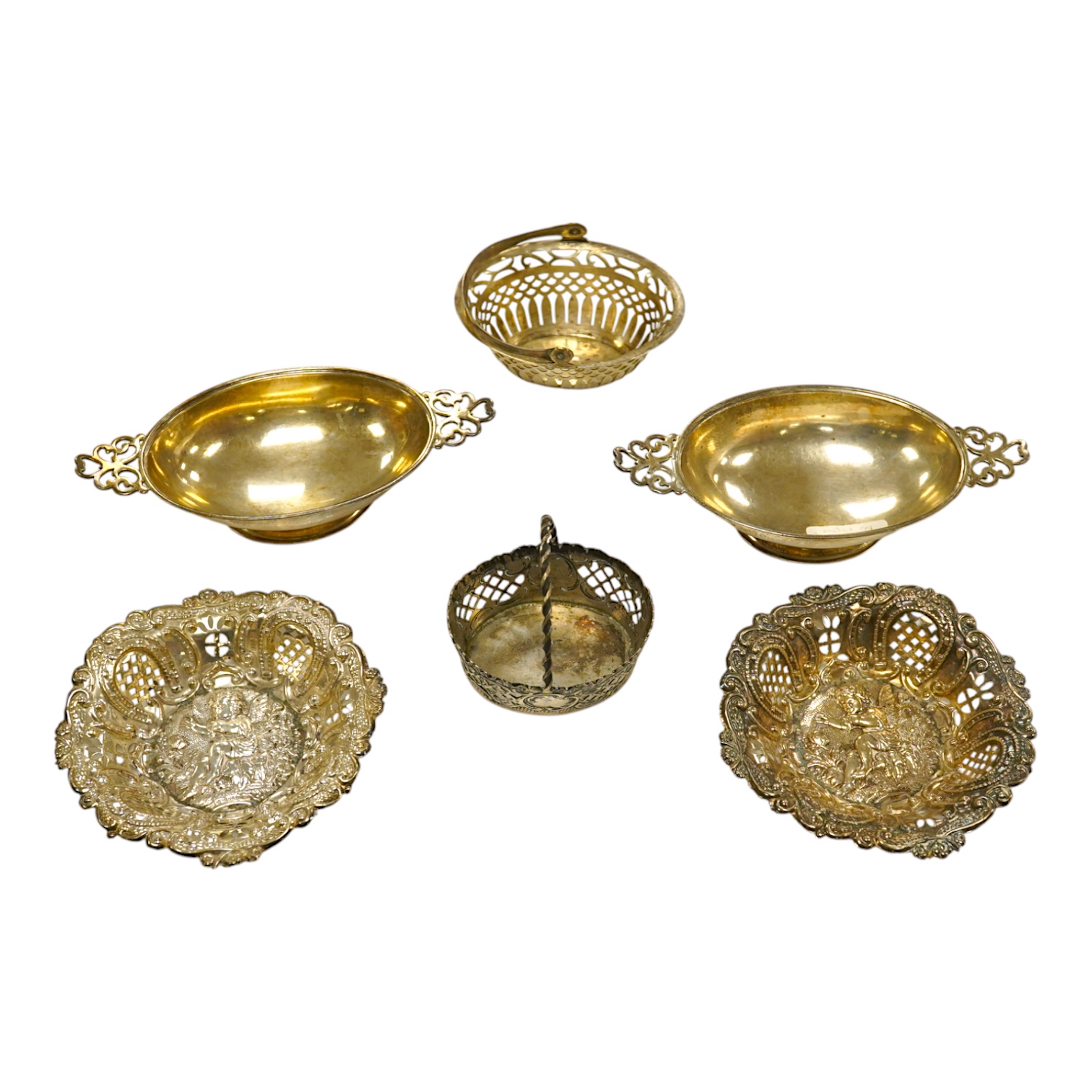 A pair of Edwardian pierced white metal dishes embossed with cherubs, a pair of two handled silver oval bowls, Birmingham, 1936 and two small baskets, one silver one 800 standard. Condition - poor to fair